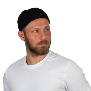 May include: A man wearing a white t-shirt, black jeans, and a black beanie.