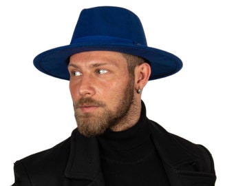 May include: A man wearing a black turtleneck sweater and a black coat with a blue fedora hat.
