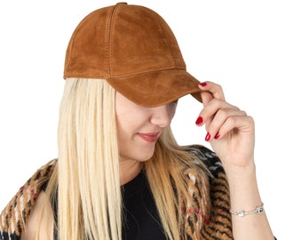 May include: A brown suede baseball cap with a curved brim. The cap is being worn by a person with long blonde hair.