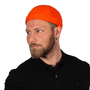 May include: Bright orange skull cap. The hat is made of a solid colour fabric and has a rounded crown and a folded brim. The hat is worn by a person wearing a black polo shirt.