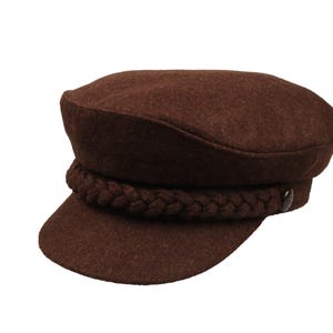 Peut inclure: Une casquette de marin en feutre marron avec une bande tressée autour de la couronne.