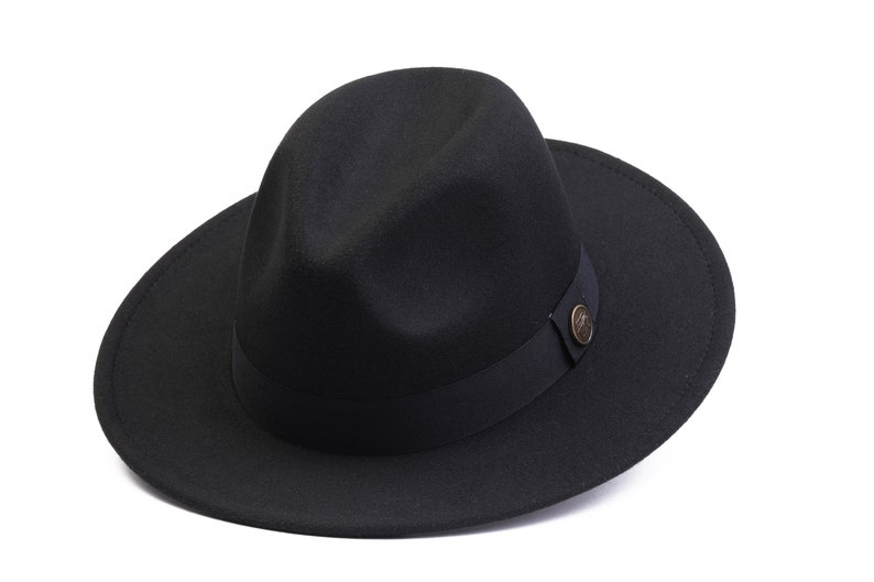 May include: A black fedora hat with a wide brim and a black ribbon band. The hat has a small, round, gold-colored button on the band.