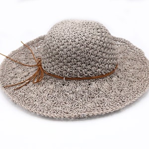 May include: A light brown crocheted sun hat with a brown leather band and a knotted tassel.