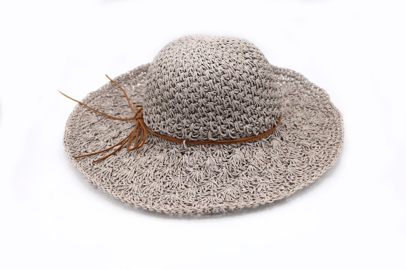 May include: A light brown crocheted sun hat with a brown leather band and a knotted tassel.