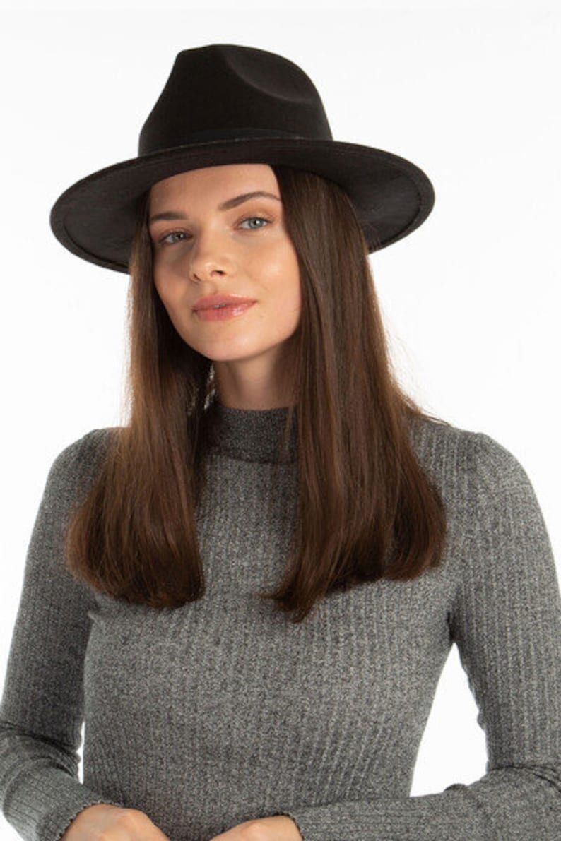 May include: A black fedora hat with a wide brim. The hat is made of a soft, felt-like material.