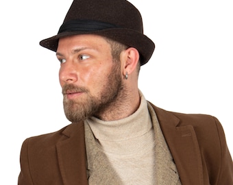 May include: A man wearing a brown fedora with a black band and a brown coat over a beige turtleneck sweater.
