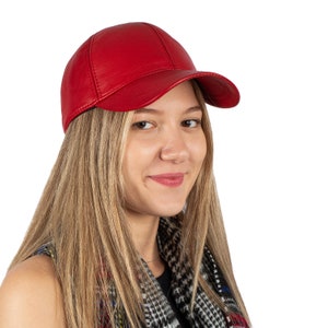 May include: A woman wearing a red leather baseball cap with a black and white patterned scarf.
