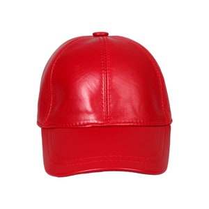 Op de afbeelding: Een felrode baseballcap met een gebogen klep. De cap is gemaakt van een glad, glanzend materiaal, waarschijnlijk leer, en heeft een klein knoopje bovenop. Een opvallend modeaccessoire.