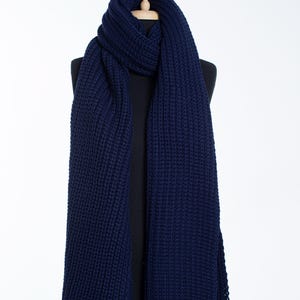 May include: A navy blue knitted scarf with a chunky knit texture. The scarf is displayed on a mannequin.