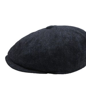 May include: A dark gray newsboy cap with a herringbone pattern. The cap has a rounded crown and a small, stiff brim. This classic style is suitable for various occasions and adds a touch of sophistication.