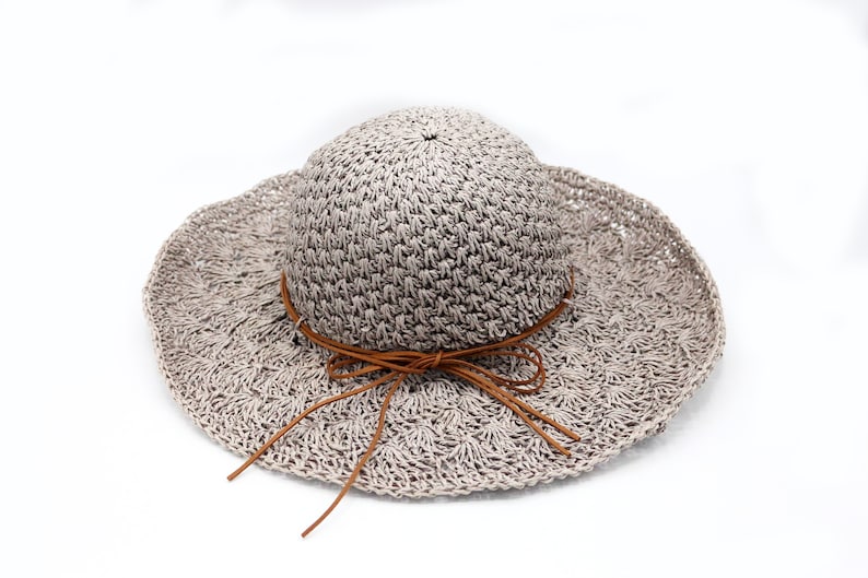 May include: A light gray crocheted sun hat with a brown leather ribbon tied in a bow.