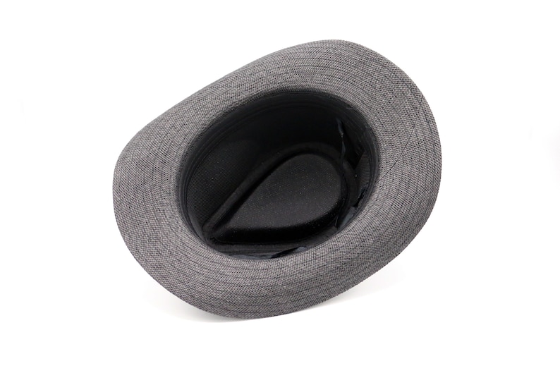 K&ouml;nnte beinhalten: Ein grauer Fedora-Hut mit schwarzem Stofffutter. Der Hut ist auf links gedreht und zeigt das Futter.