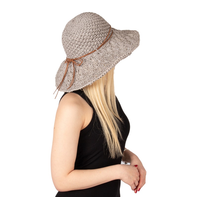 May include: A gray crochet sun hat with a brown ribbon tied in a bow. The hat has a wide brim and is worn by a person with long blonde hair.