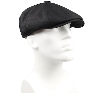 May include: A black newsboy cap with a textured fabric. The cap has a rounded crown and a short brim.