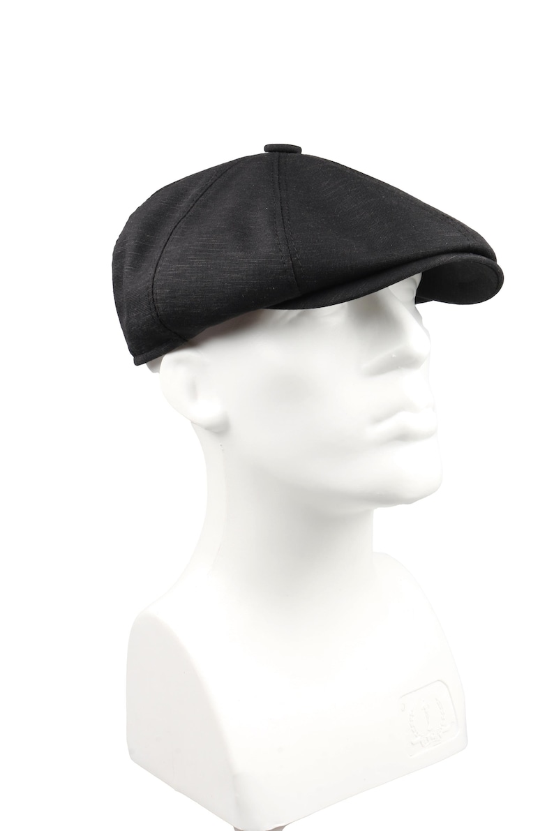 May include: A black newsboy cap with a textured fabric. The cap has a rounded crown and a short brim.