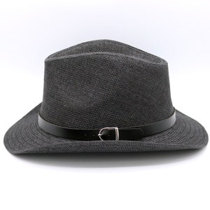 K&ouml;nnte beinhalten: Ein schwarzer Fedora-Hut mit einem schwarzen Lederband und einer silbernen Schnalle.