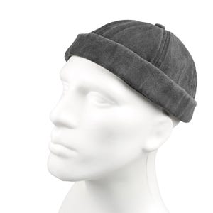 May include: A dark gray, rolled-brim beanie hat. The hat is made of a soft, textured fabric and sits on a white mannequin head. The hat's brim is folded up, and the crown is slightly rounded.