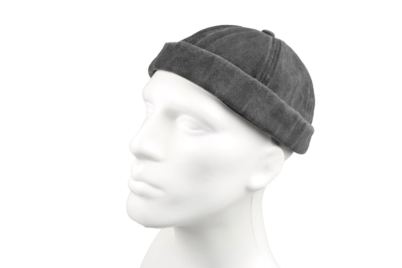 May include: A dark gray, rolled-brim beanie hat. The hat is made of a soft, textured fabric and sits on a white mannequin head. The hat's brim is folded up, and the crown is slightly rounded.