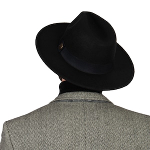 May include: A black felt fedora hat with a black grosgrain ribbon and a gold button.