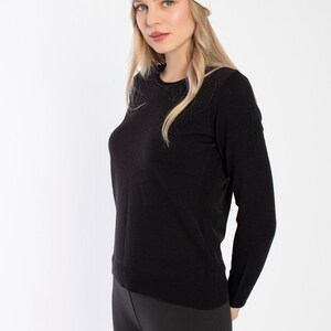 K&ouml;nnte beinhalten: Eine Frau tr&auml;gt einen schwarzen Langarm-Pullover und schwarze Leggings mit einer wei&szlig;en M&uuml;tze.