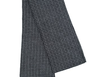 May include: A black and gray patterned scarf with black fringe.