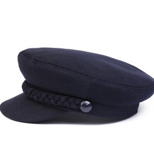 Peut inclure: Une casquette de marin en laine bleu marine avec une bande tressée et un seul bouton.