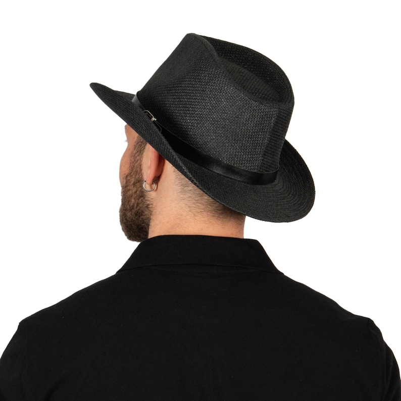K&ouml;nnte beinhalten: Ein schwarzer Fedora-Hut mit breiter Krempe und einem schwarzen Band um die Krone.
