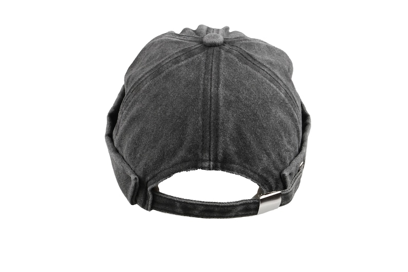 May include: A dark gray, washed-look baseball cap with a curved brim and adjustable strap. The cap features a button on top and a metal buckle closure at the back. The hat is made of a soft, textured fabric.