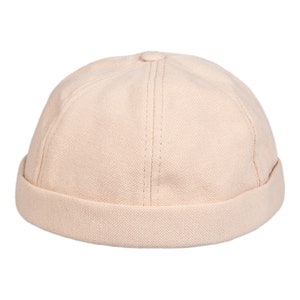 May include: A light pink cotton beanie with a rolled brim.