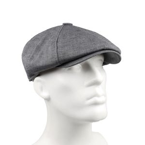 May include: A gray newsboy cap with a rounded crown and a short, stiff brim. The hat is made of a textured fabric and is displayed on a white mannequin head. This classic style is suitable for various outfits.