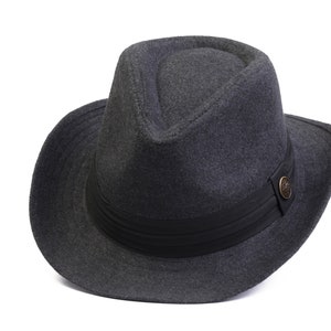 Może przedstawiać: Szary kapelusz fedora z czarną wstążką i małym, okrągłym, mosiężnym guzikiem z boku.