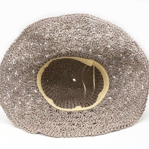 May include: A light brown crocheted sun hat with a cream colored lining. The hat is made of a woven material and has a wide brim.