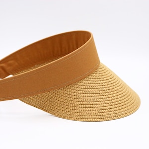 Puede incluir: Una visera de paja marrón con una banda de tela marrón.