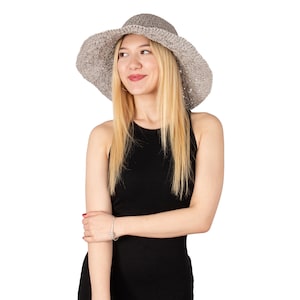 May include: A woman wearing a gray crochet sun hat and a black sleeveless dress.