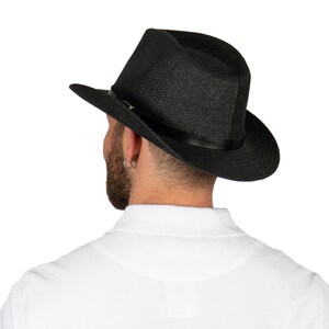 K&ouml;nnte beinhalten: Ein schwarzer Fedora-Hut mit breiter Krempe. Der Hut ist aus gewebtem Material und hat ein schwarzes Band um die Krone.