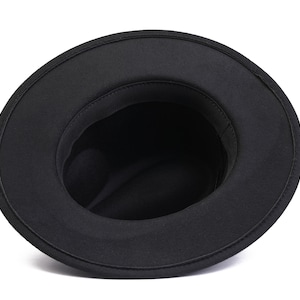 May include: Black fedora hat with a wide brim and a soft, felt texture. The hat is turned inside out, showing the lining.