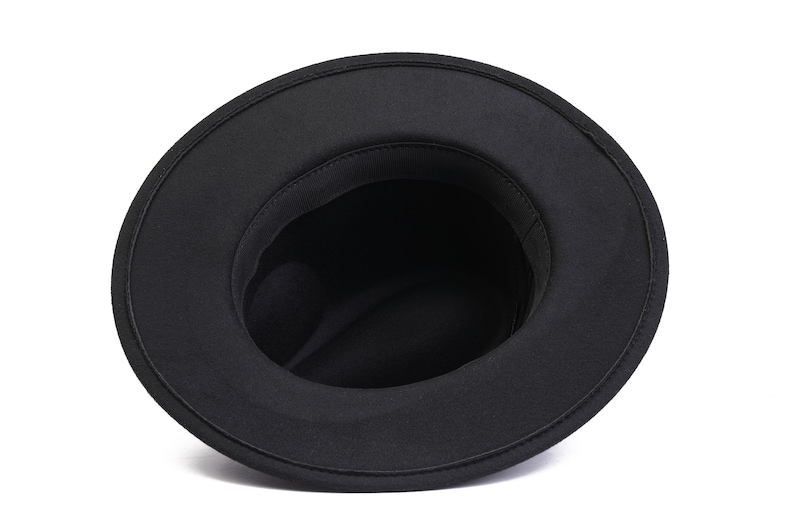May include: Black fedora hat with a wide brim and a soft, felt texture. The hat is turned inside out, showing the lining.