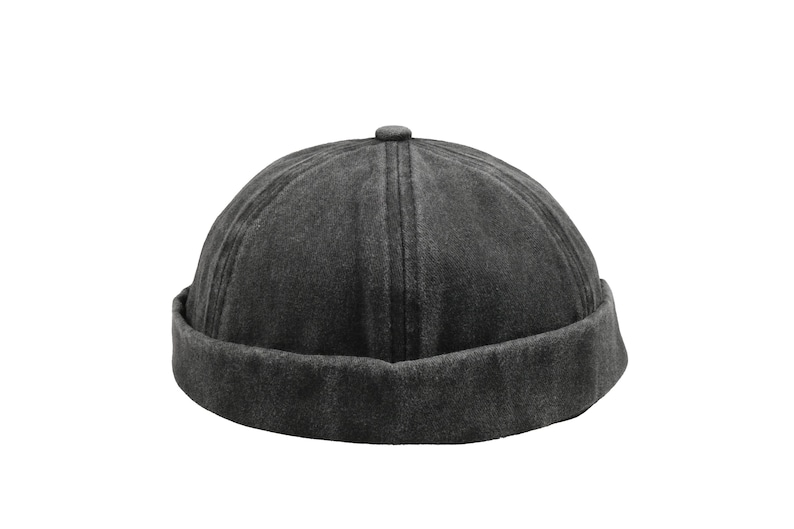 May include: A dark gray, brimless skull cap with a rounded crown and a folded-up brim. The hat has a textured appearance and a small button detail at the top. The hat is a casual accessory.