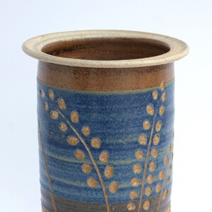 May include: A brown ceramic vase with a blue and brown glaze. The vase has a wide mouth and a narrow base. It is decorated with a pattern of stylized leaves and dots.