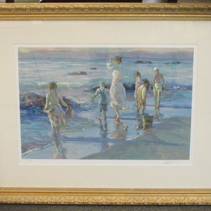 May include: A framed print of a painting depicting a family of six walking on a beach at sunset. The painting is done in a soft, impressionistic style with muted colors of blue, pink, and white. The family is walking towards the viewer, and the waves are gently lapping at their feet.