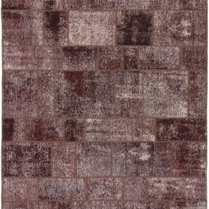 Könnte beinhalten: Ein Patchwork-Teppich in Braun- und Weißtönen. Der Teppich besteht aus verschiedenen Stoffstücken, die zusammengenäht wurden, um ein einzigartiges Design zu schaffen.
