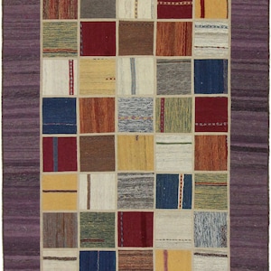 Könnte beinhalten: Ein bunter Patchwork-Teppich mit einem violetten Rand. Der Teppich besteht aus Quadraten in verschiedenen Farben und Mustern, darunter Rot, Blau, Gelb und Grün.