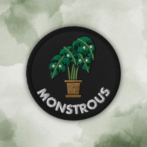 Può includere: Toppa ricamata nera con una pianta verde in un vaso marrone e la parola "MONSTROUS" in testo bianco.