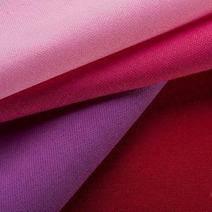 May include: An abstract image of folded fabric in shades of pink, magenta, purple, and red. The layered fabric creates a textured, colourful display. The varying hues create a gradient effect, with a range of tones.