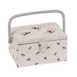 May include: A rectangular sewing box with a light grey fabric exterior, decorated with a repeating pattern of bees in yellow, black, and white. The lid has embroidered bees. It has a grey handle and a button closure.