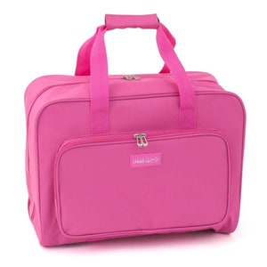 May include: A vibrant pink sewing machine carry case with a top handle and shoulder straps. The case features a front zipped pocket and the text "Happy Girls". Designed for carrying a sewing machine and accessories, it is a practical item.