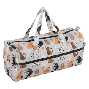 May include: A grey duffel bag featuring a repeating pattern of cats in orange, brown, black, and white. The bag has black zips, a handle, and a tag that says "Happy Go Lucky".
