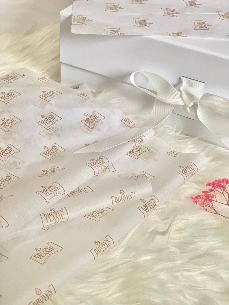 May include: White gift box with a white satin ribbon and a white tissue paper with the words "Brown Flame Candles" printed on it.