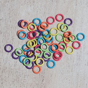 May include: A large pile of colorful plastic rings, mostly in shades of green, orange, and purple. The rings are all different sizes and are arranged in a random pattern.