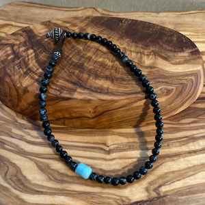 May include: Black and white agate bead bracelet with a turquoise bead accent and a silver clasp.